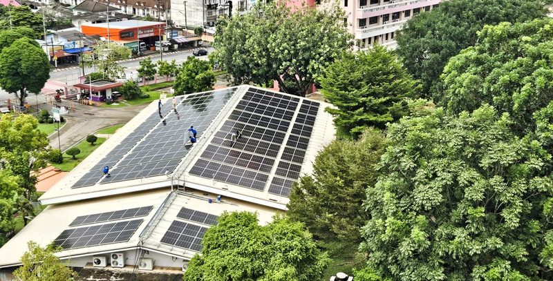 Aerial view of a large rooftop solar array on a college building in Trang